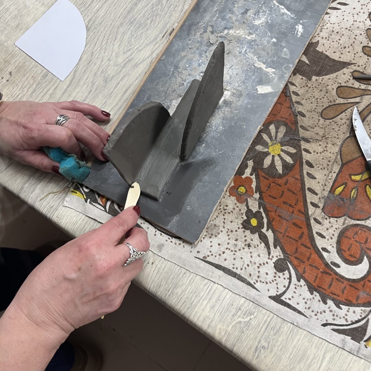 Ręczne łączenie elementów z gliny podczas tworzenia serwetnika