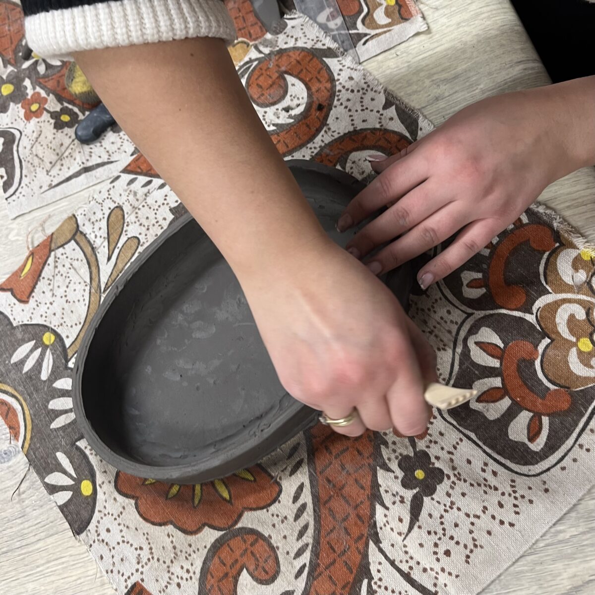 Ręczne łączenie elementów z gliny podczas tworzenia owalnego naczynia