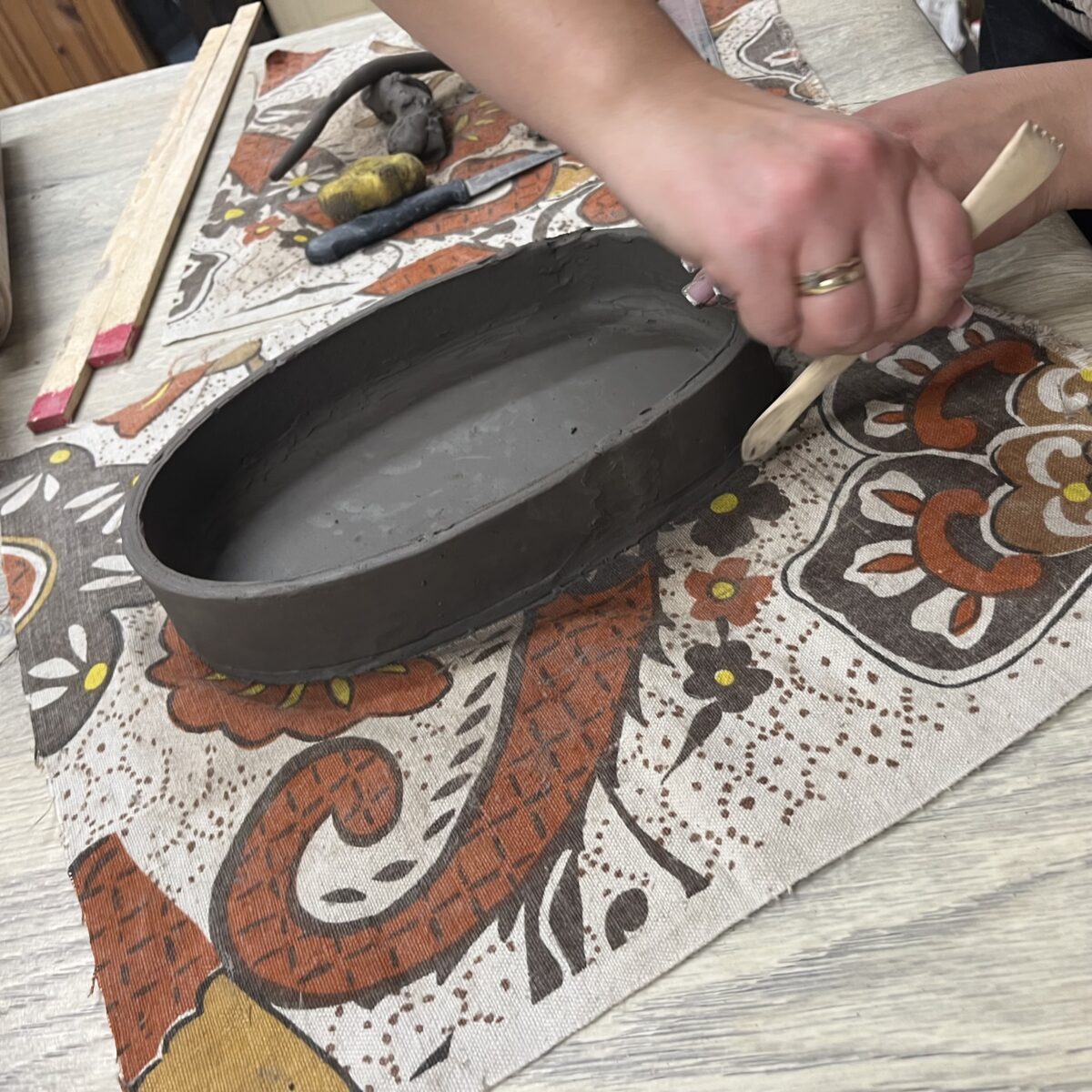 Inny widok na ręczne łączenie elementów z gliny podczas tworzenia owalnego naczynia