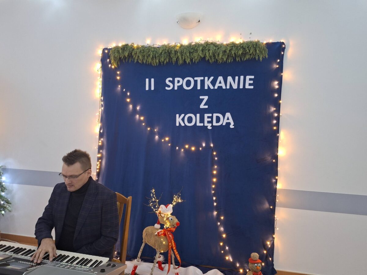 Marek Szulikowski gra na klawiszach przed ścianką z napisem "drugie spotkanie z kolędą"