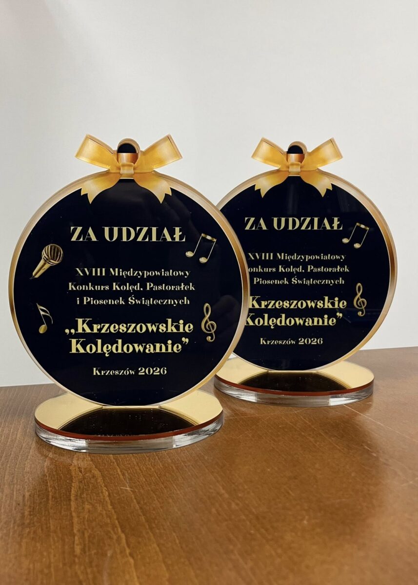 Dwie pamiątkowe statuetki w kształcie bombki z granatowym-złotym wykończeniem, z napisem ‘Za udział – XVIII Międzynarodowy Konkurs Kolęd, Pastorałek i Piosenek Świątecznych "Krzeszowskie Kolędowanie", Krzeszów 2026 które dostały nasze zespoły, Jargocianie i Brokaty