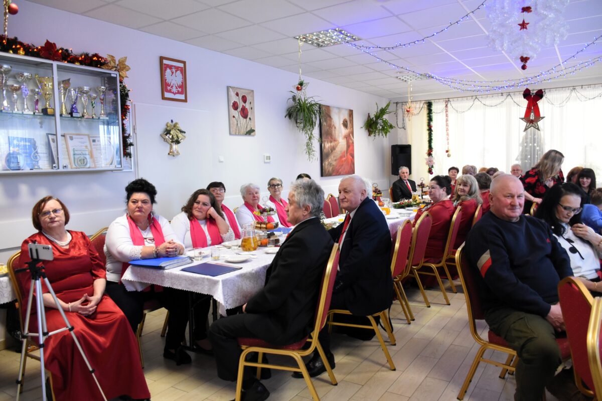 DSC_8853 Wszyscy siedzą przy stole słuchając zespół, widać zespół Brokaty i Pani Halina