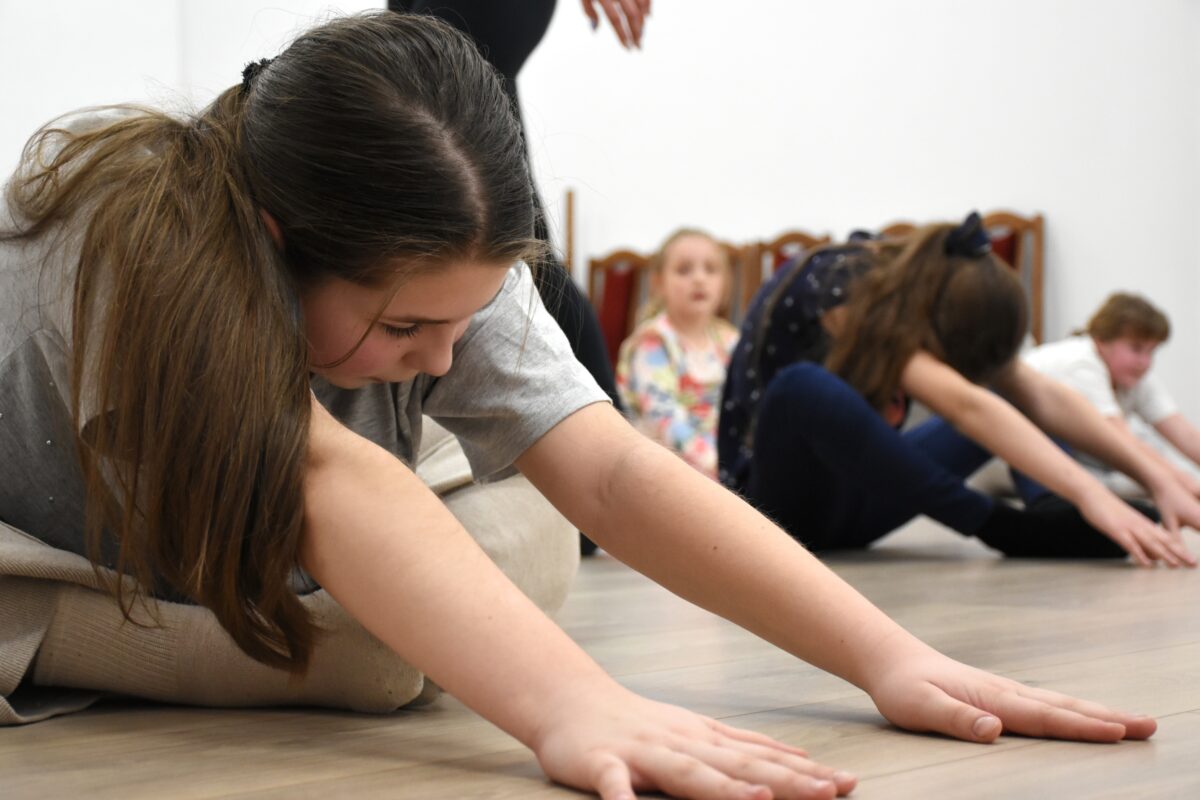 Dziewczyny dalej siedzą i robią skłon do przodu