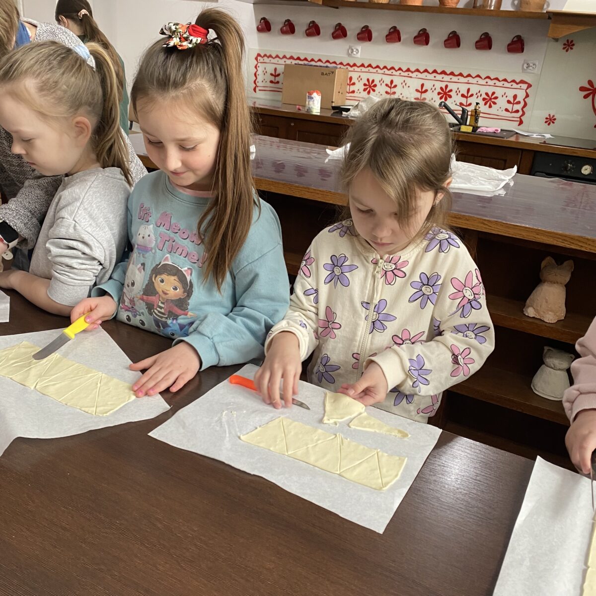 dziewczynki kroją ciasto francuskie w małe trójkąty