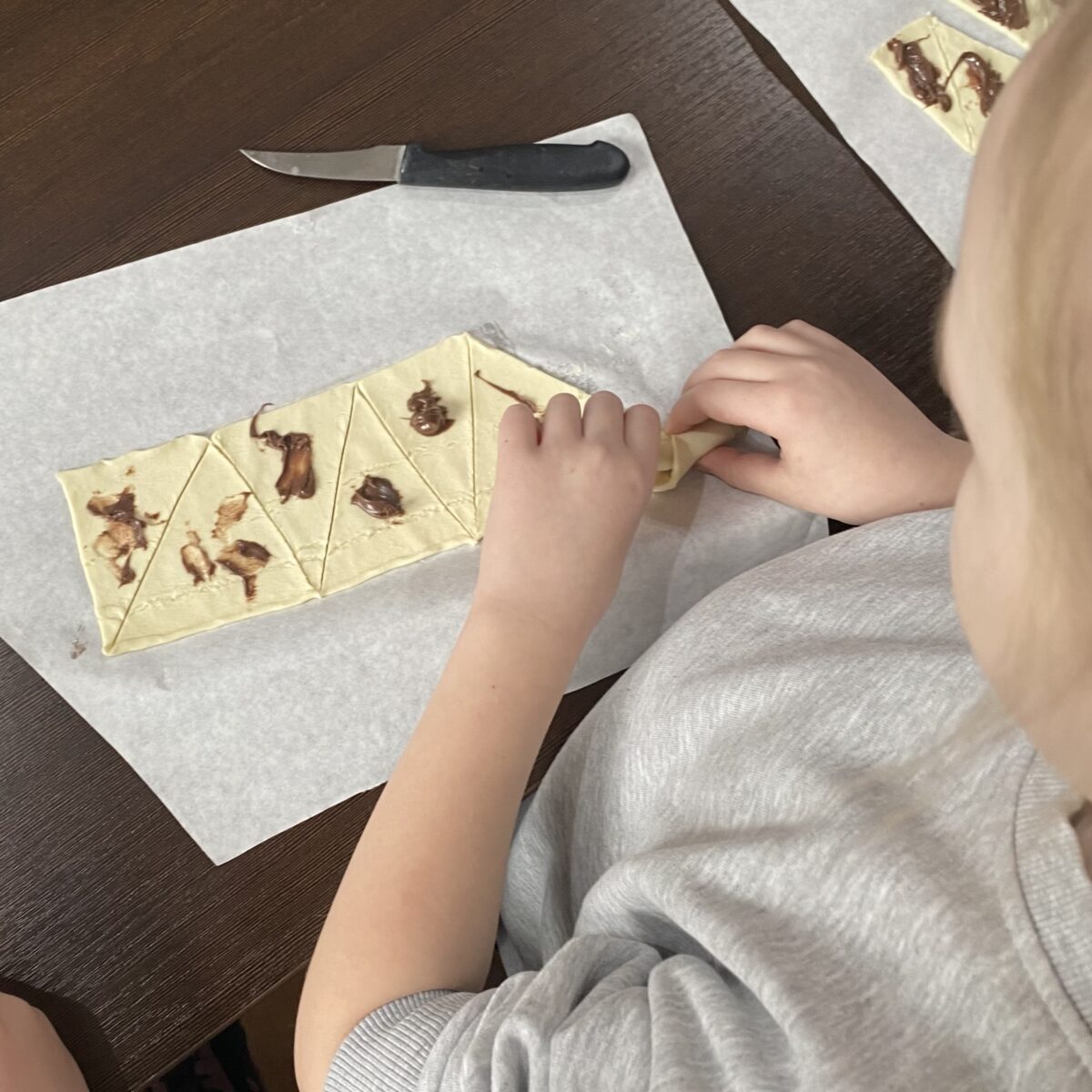 Dziewczynka zawija ciasto francuskie aby były croissanty