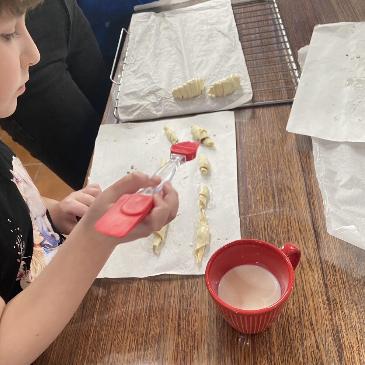 amelka smaruje croissanty z pędzelkiem moczonym w mleku