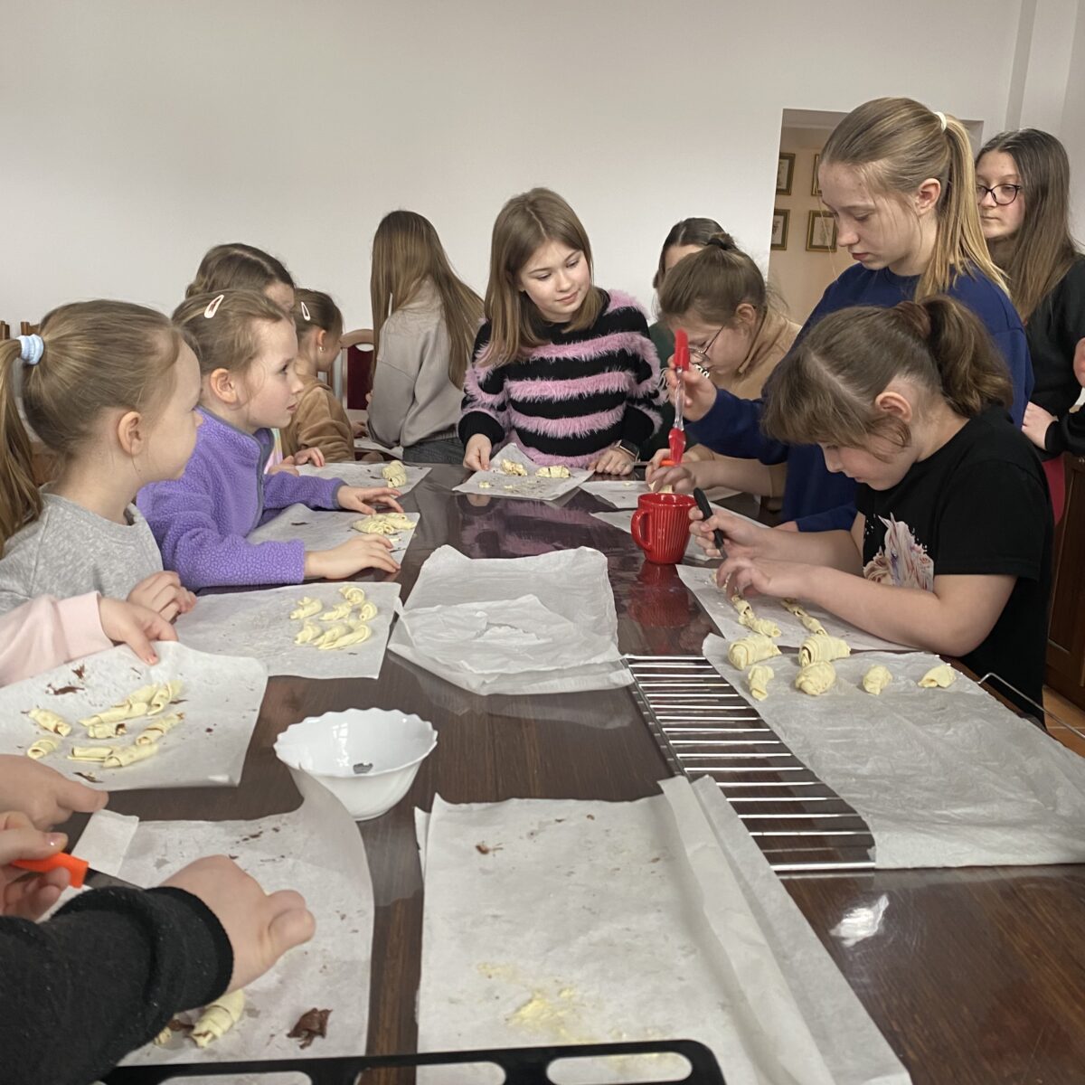 Wszystkie dzieci czekają aby kończyć croissanty przed upieczeniem