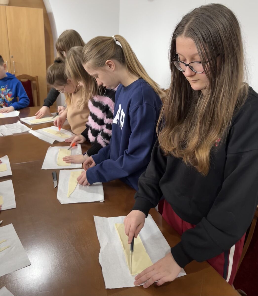 Widać dziewczyny które zaczynają kroić ciasto francuzkie