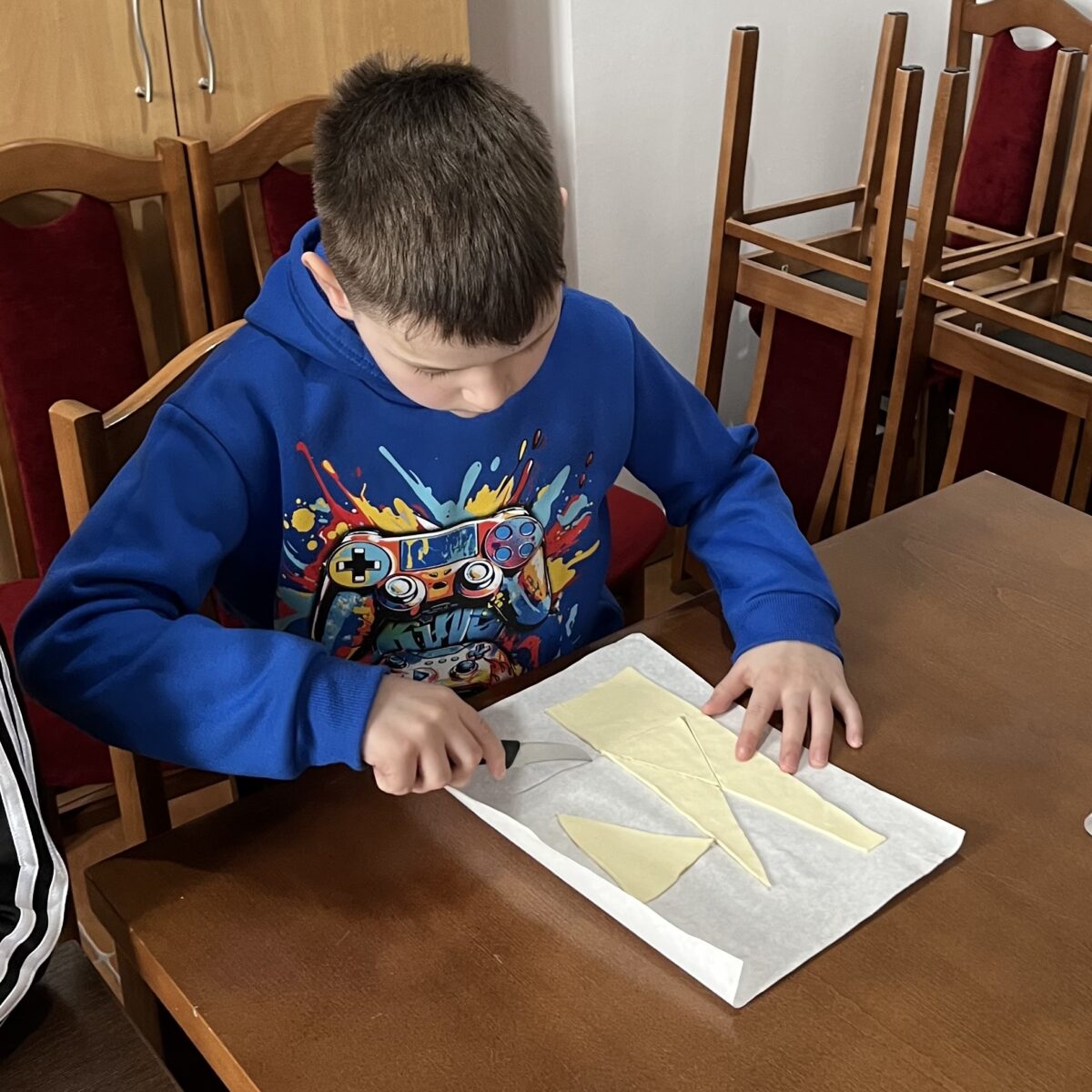 Dominik kroji ciasto francuzkie w małych trójkątach