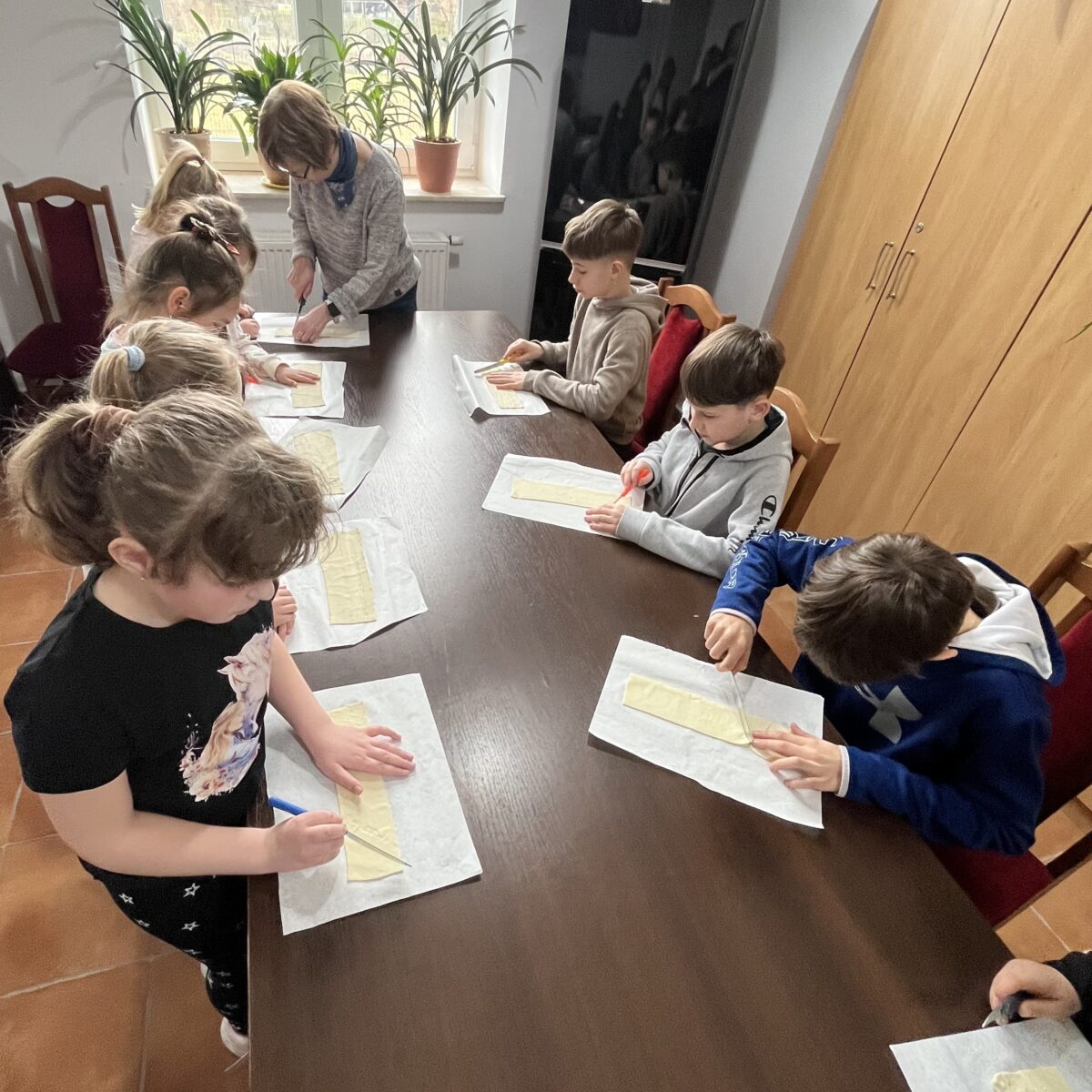 dzieci kroją ciasto francuzkie, pani Agata też pomaga