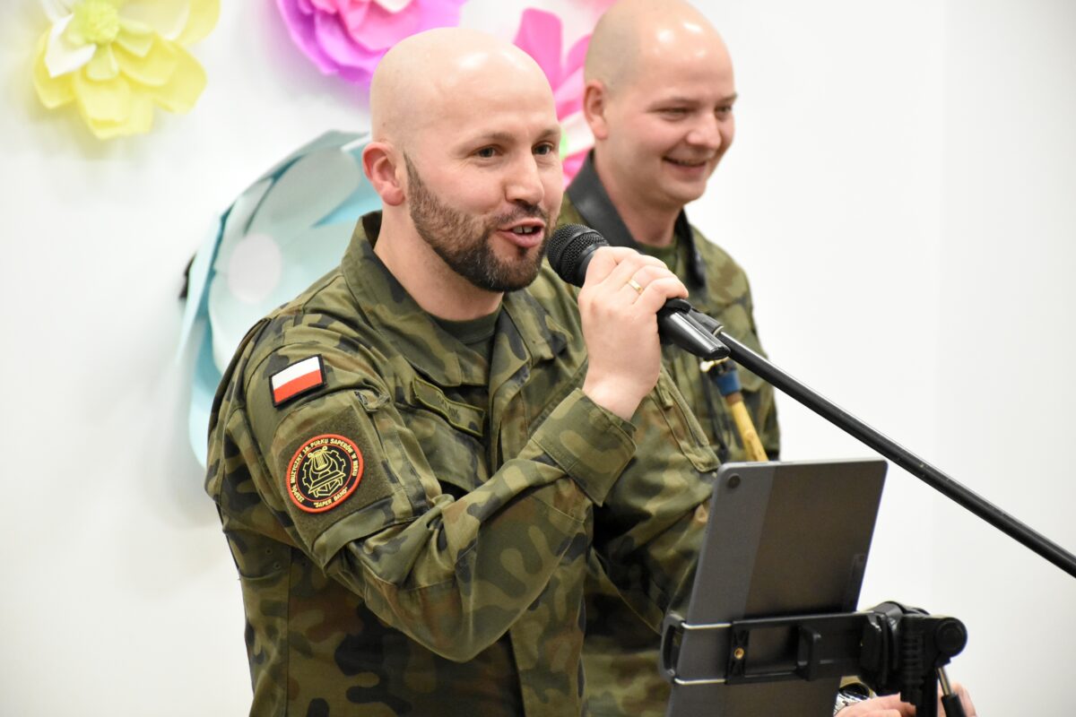 Wokalista i inny żołnierz występują z uśmiechem