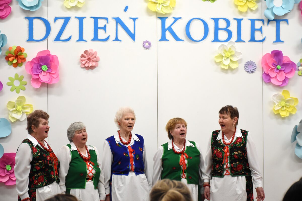 Zespół Wesołe Kumosie śpiewają przed ścianke na Dzień Kobiet
