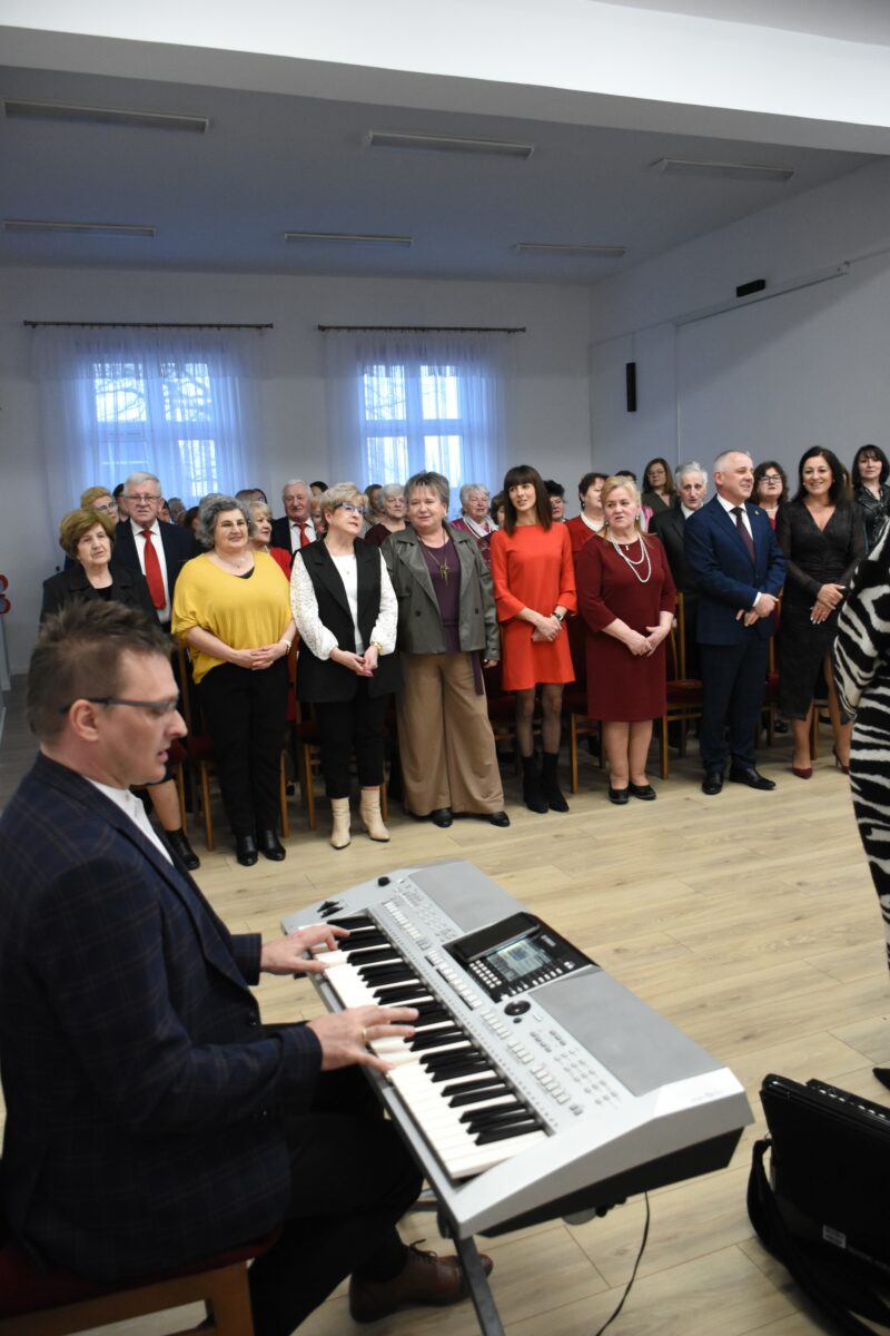 Wszyscy śpiewają sto lat na tle i Marek Szulikowski gra na klawiszaw