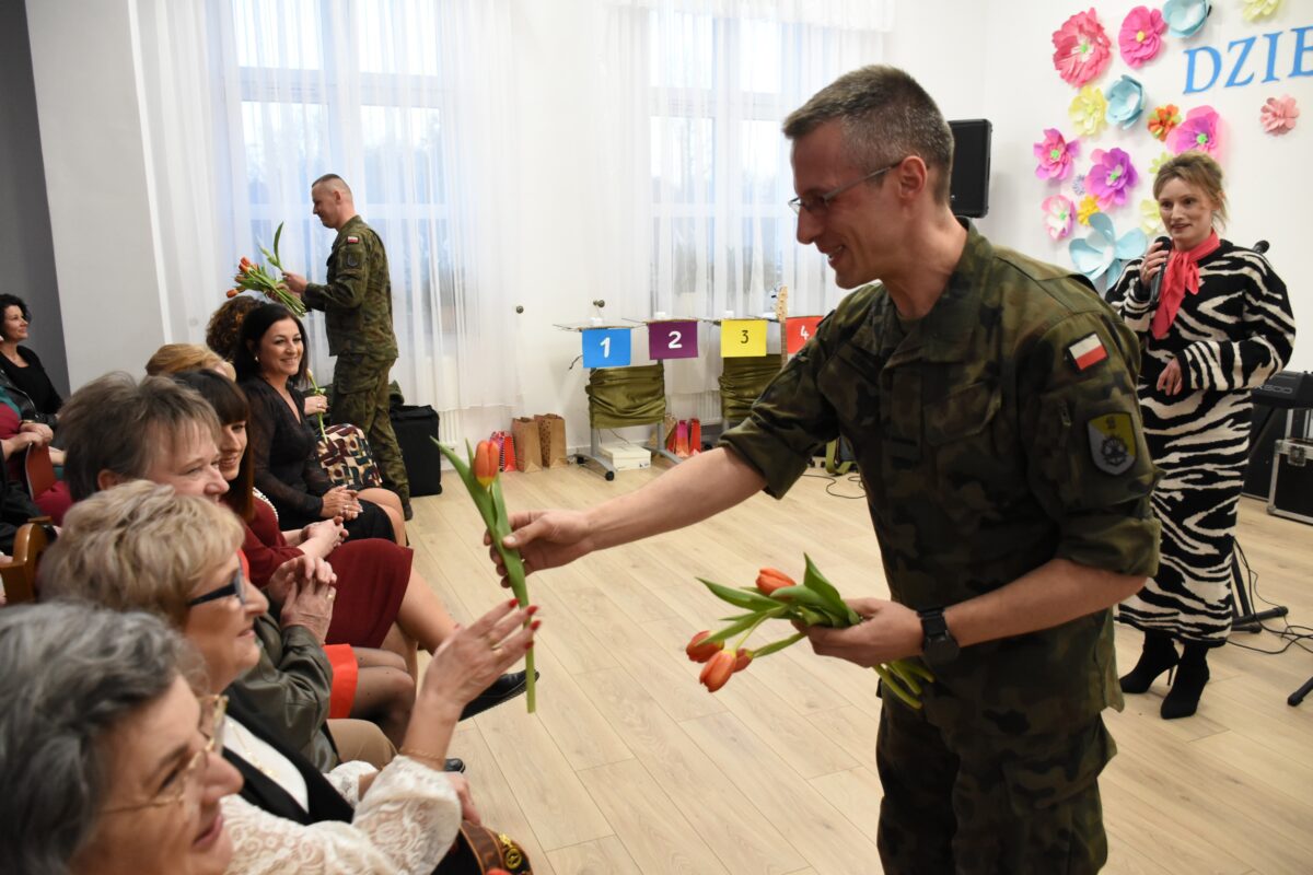 Żołnierz daje kwiaty paniom z uśmiechem