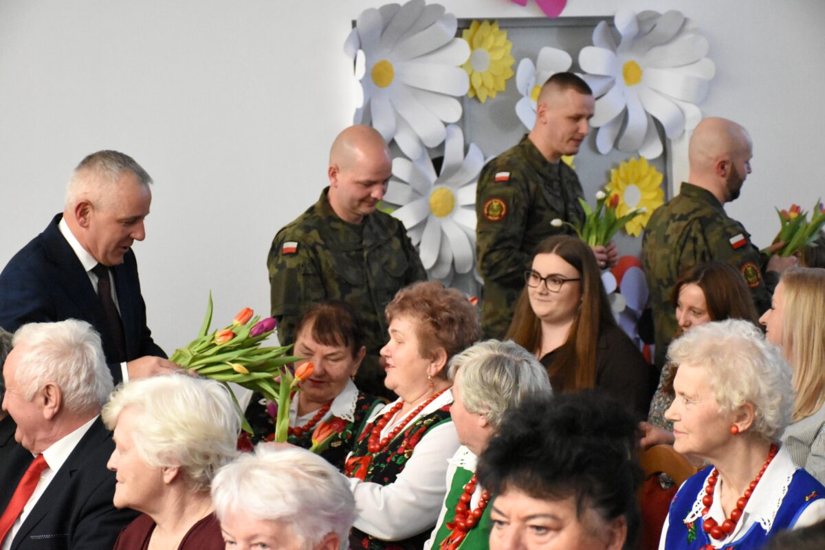 Pan Wójt Tomasz Podpora i żołnierzy chodzą po sali aby podać paniom kwiatek