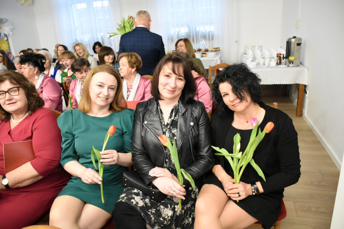 Kobiety z kwiatkiem w ręcach pozują z uśmiechem