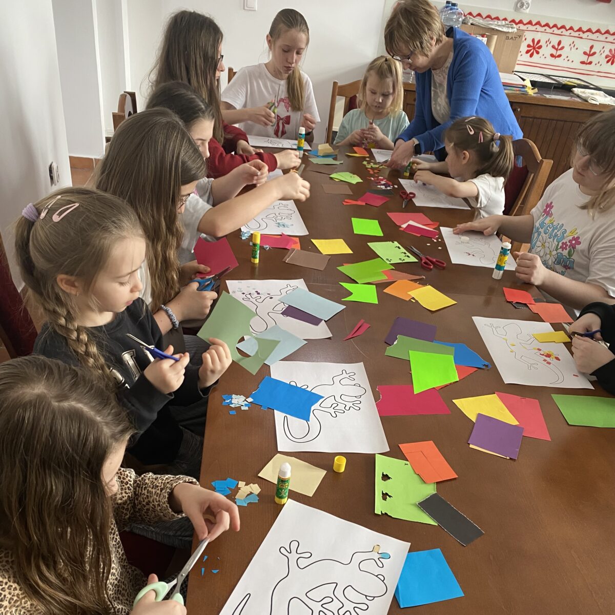 Pani Agata pomaga dzieciom obcinać papierki