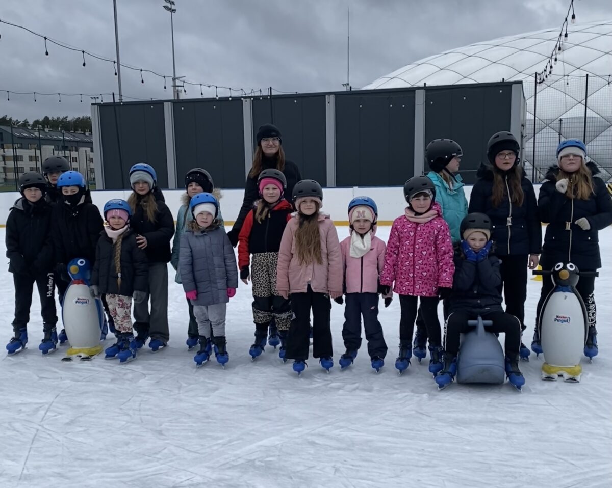 Dzieci z pani Isabellą pozują na łyżwach do zdjęcia