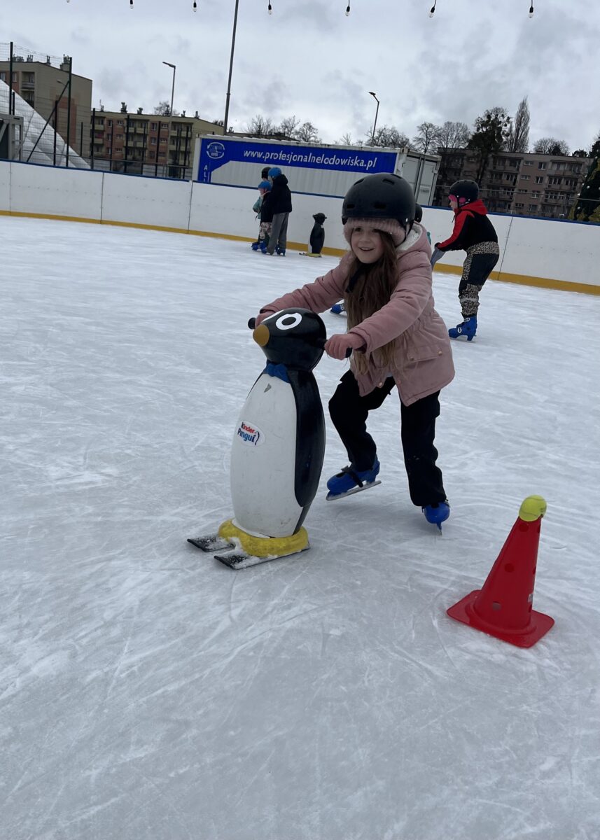 Marcelina z dużym uśmiechem kończy wyścig z pingwinami na łyżwach