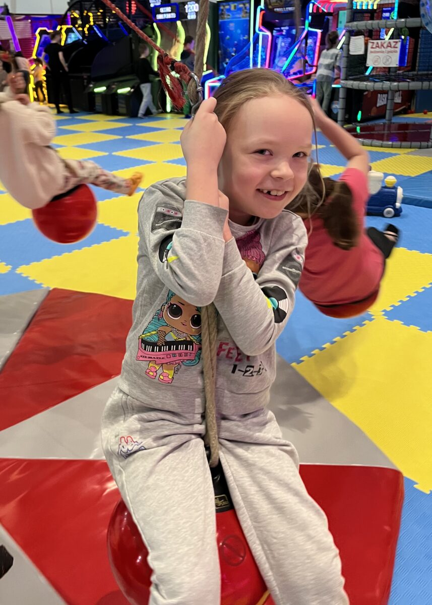 Marysia z uśmiechem się trzyma kulki która wisi i rusza się w okół punktu