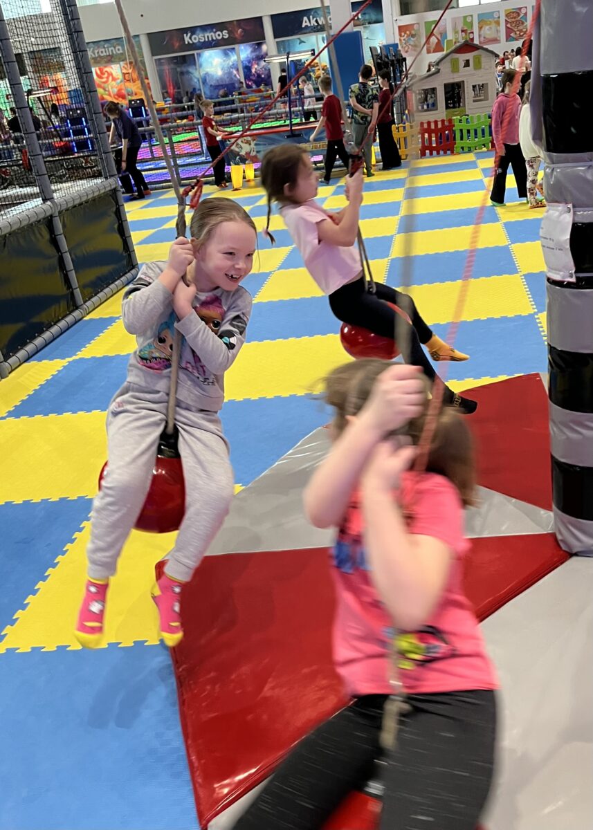 dziewczyny z uśmiechem się trzymają kulki która wisi i rusza się w okół punktu