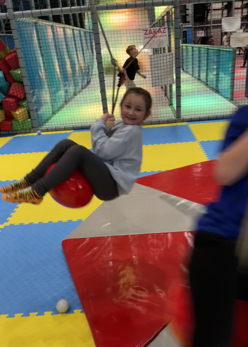 Michalina z dużym uśmiechem się trzyma kulki która wisi i rusza się w okół punktu