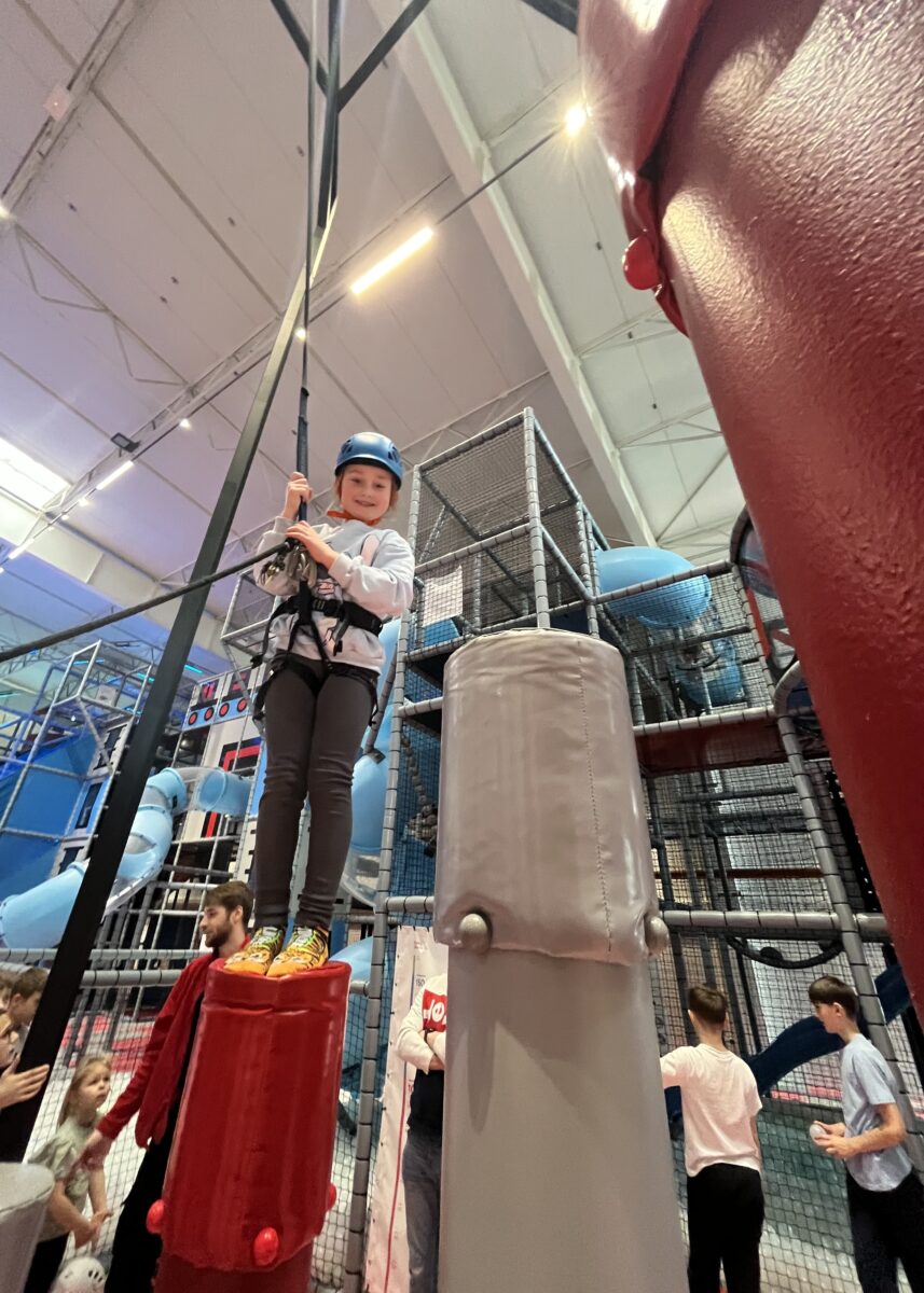 Michalina stoi dumnie na wysokim słupku, z dużym uśmiechem